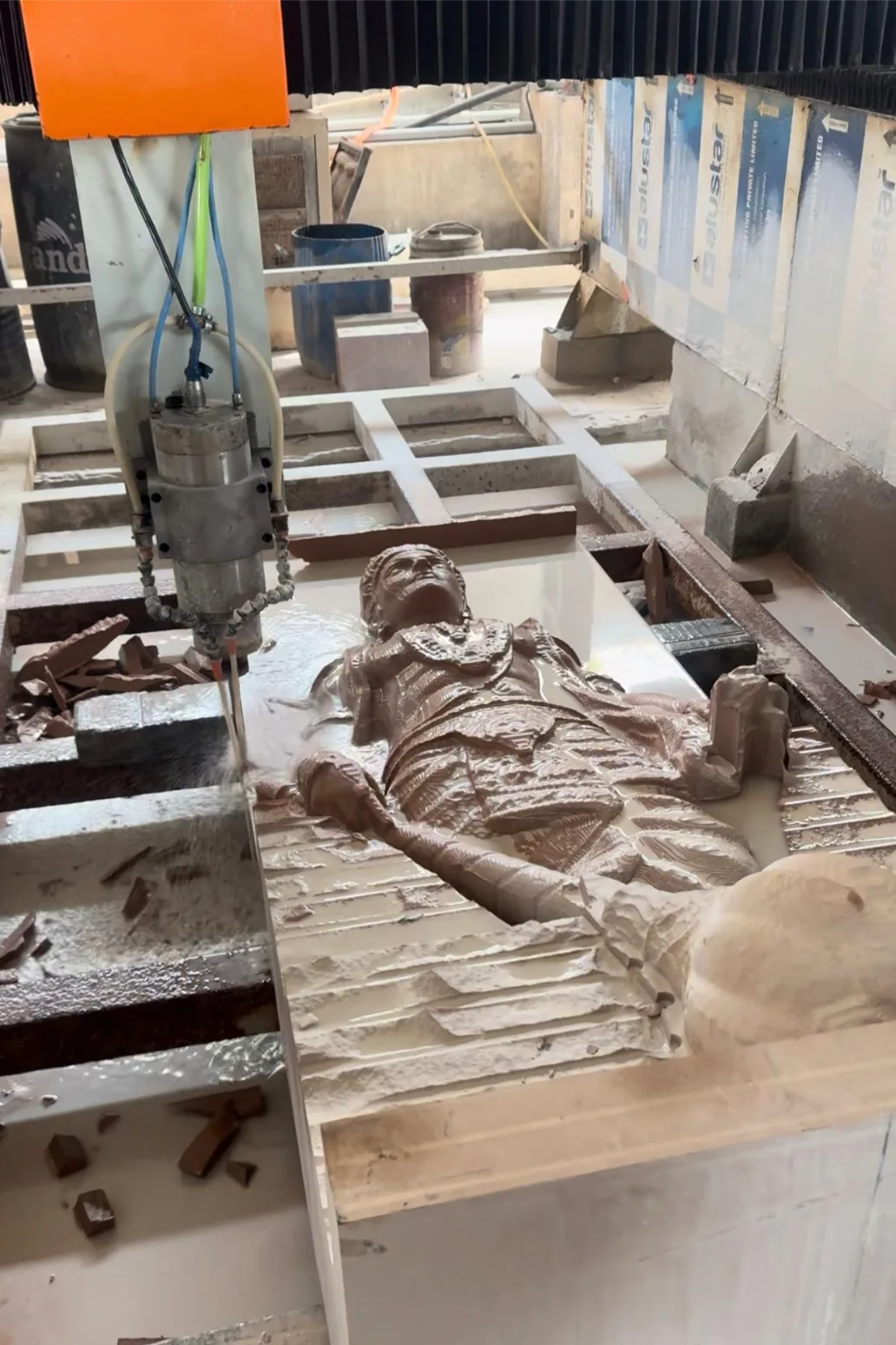 CNC router carving a reclining figure relief in marble