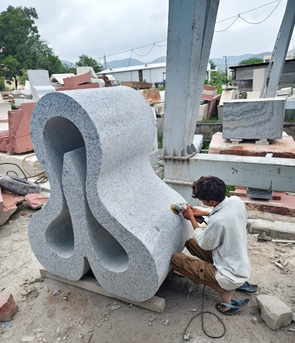 Craftsman finishing an abstract granite sculpture