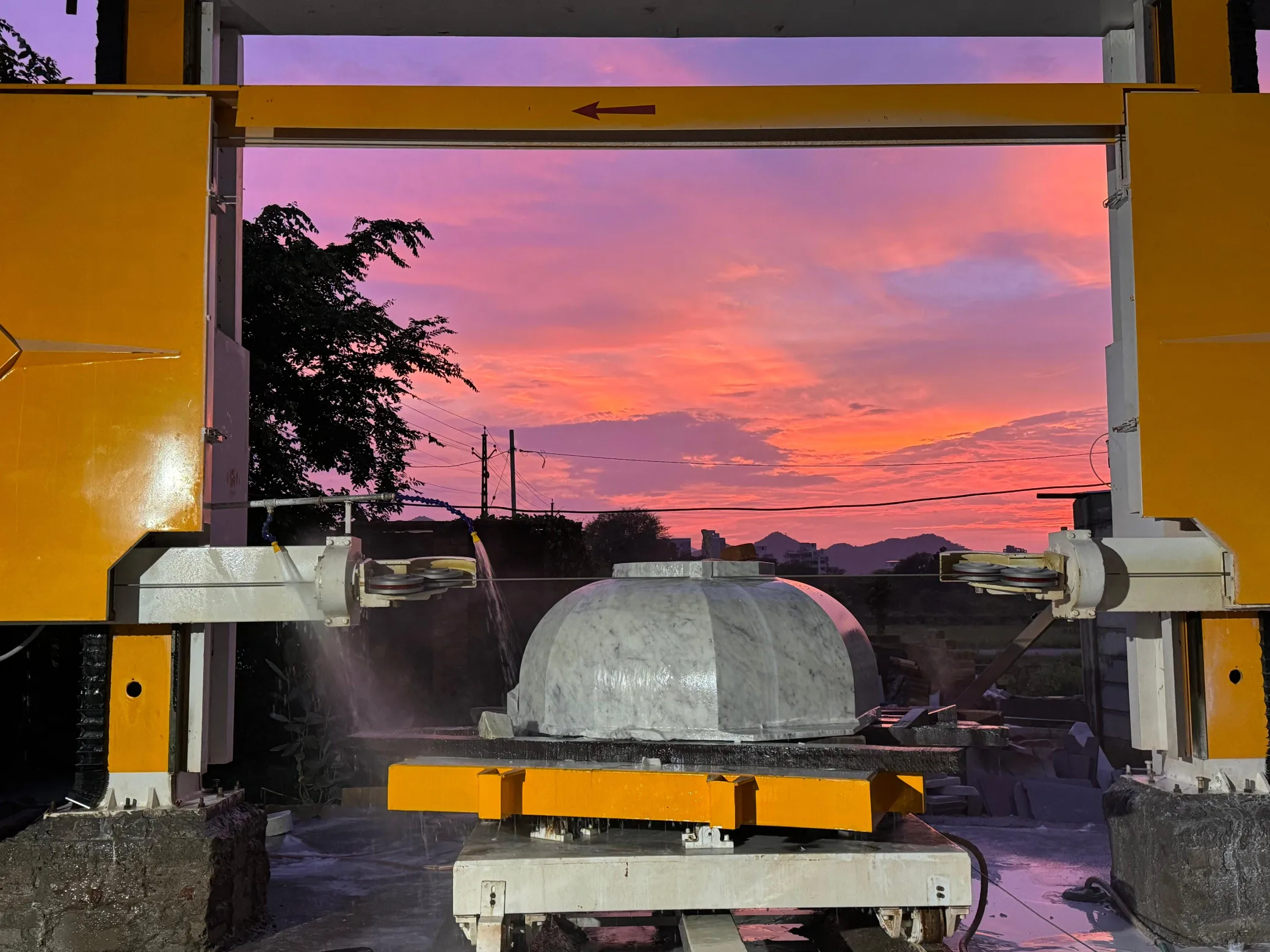 CNC wire saw cutting a stone dome at sunset
