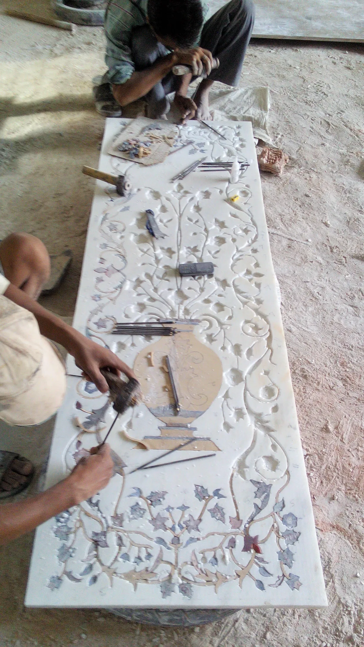 Artisans hand-carving an ornamental marble panel