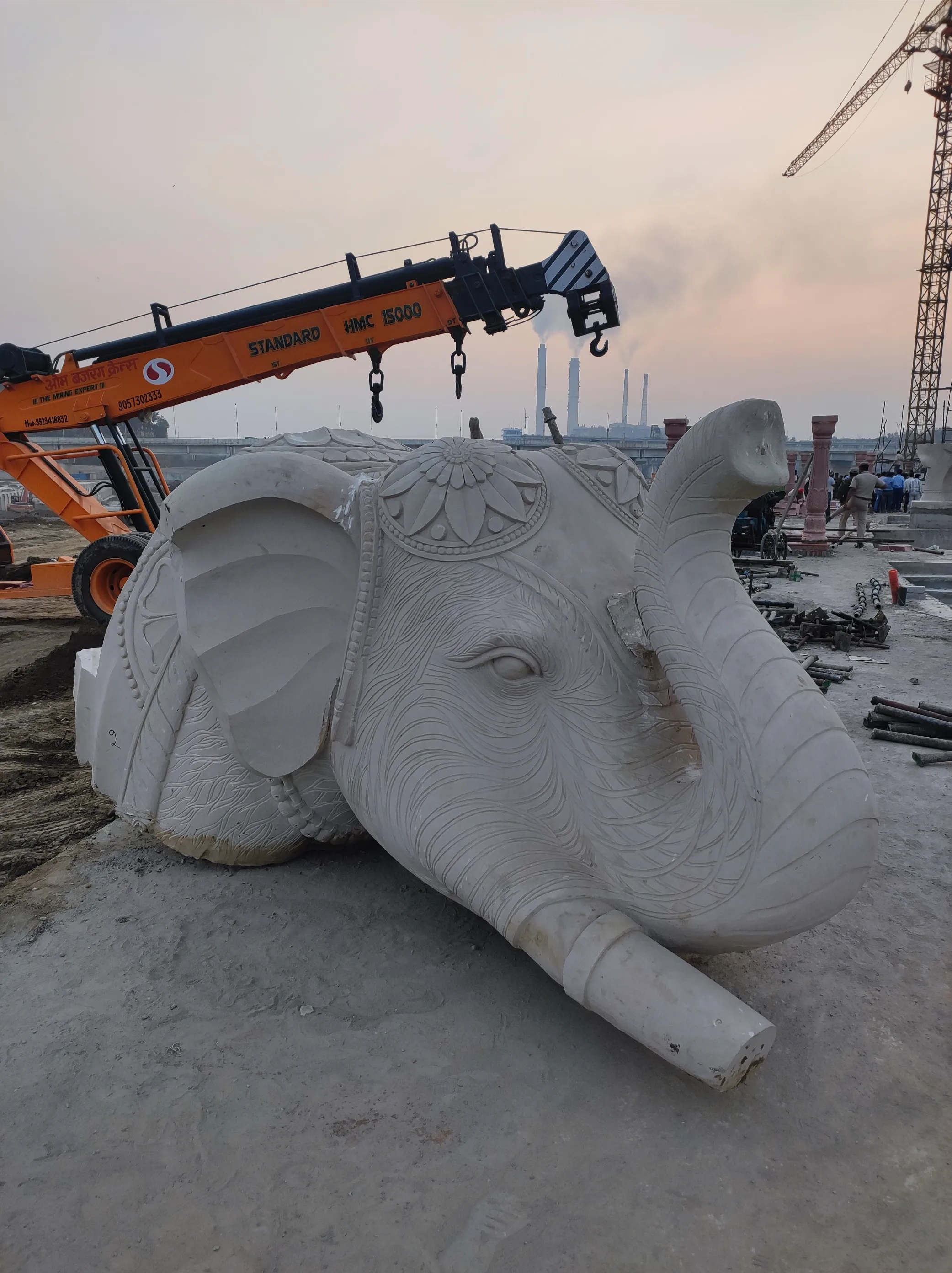 Large carved stone elephant lifted by crane