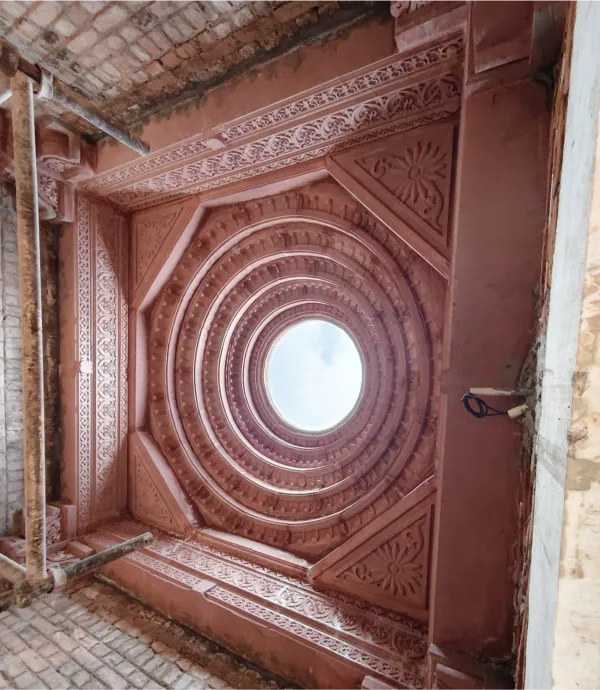 Carved red sandstone ceiling with a circular skylight