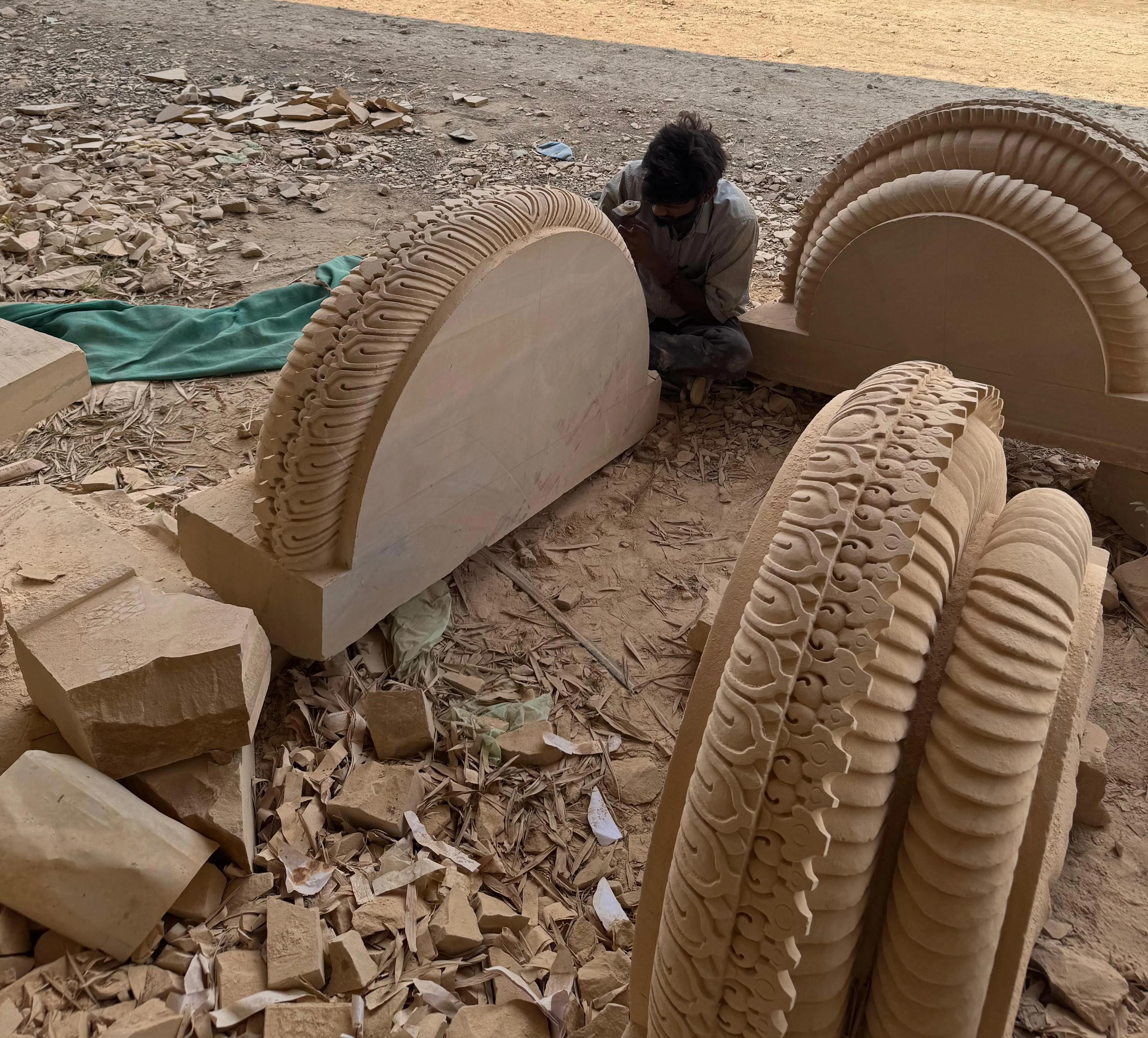 Artisan hand-carving semicircular sandstone arch pieces with ornate carved borders