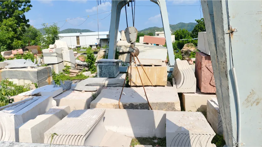 Stone yard with gantry crane lifting natural stone blocks