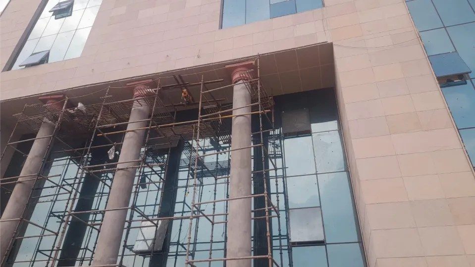 Stone columns and glass façade during installation – CBSE Headquarters, Dwarka, Delhi