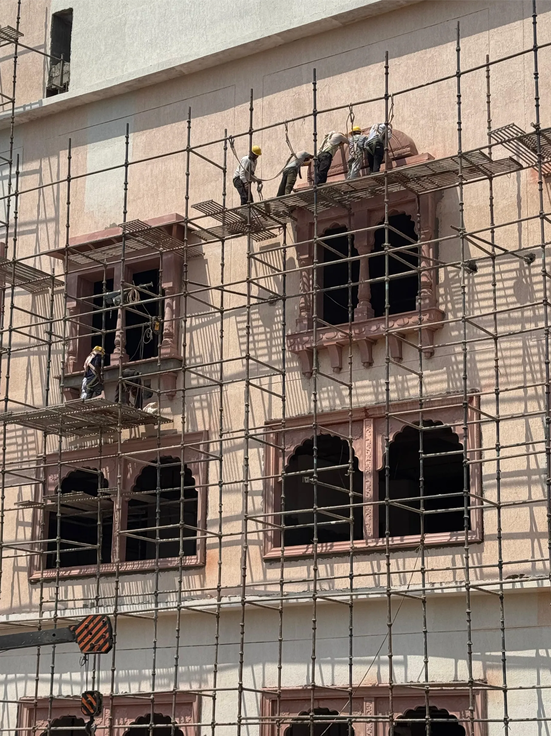 Workers fixing arched sandstone windows – Jaipur Junction Redevelopment, Jaipur