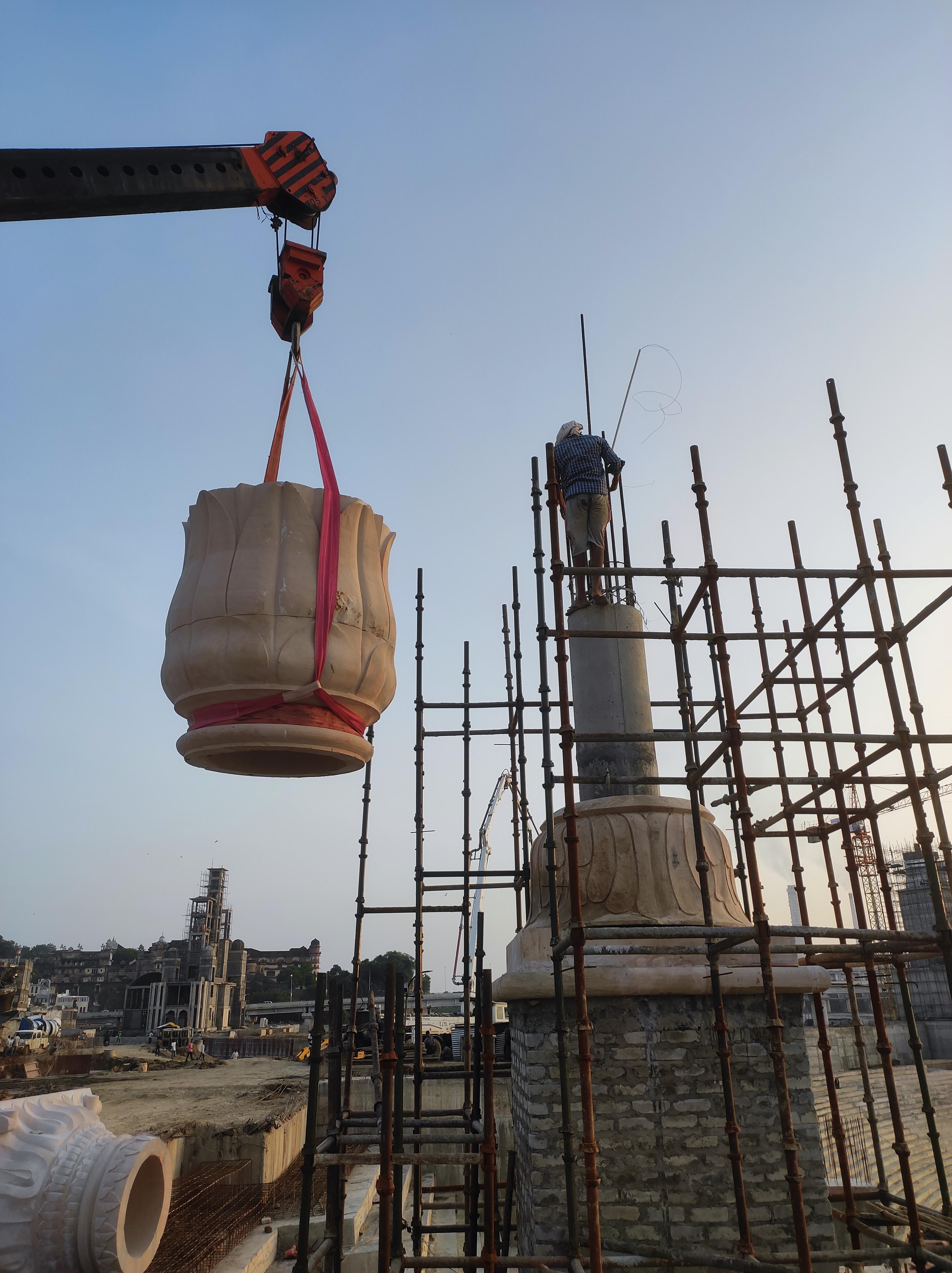 Carved stone urn lifted by crane onto a tower under construction – Kota Riverfront, Kota