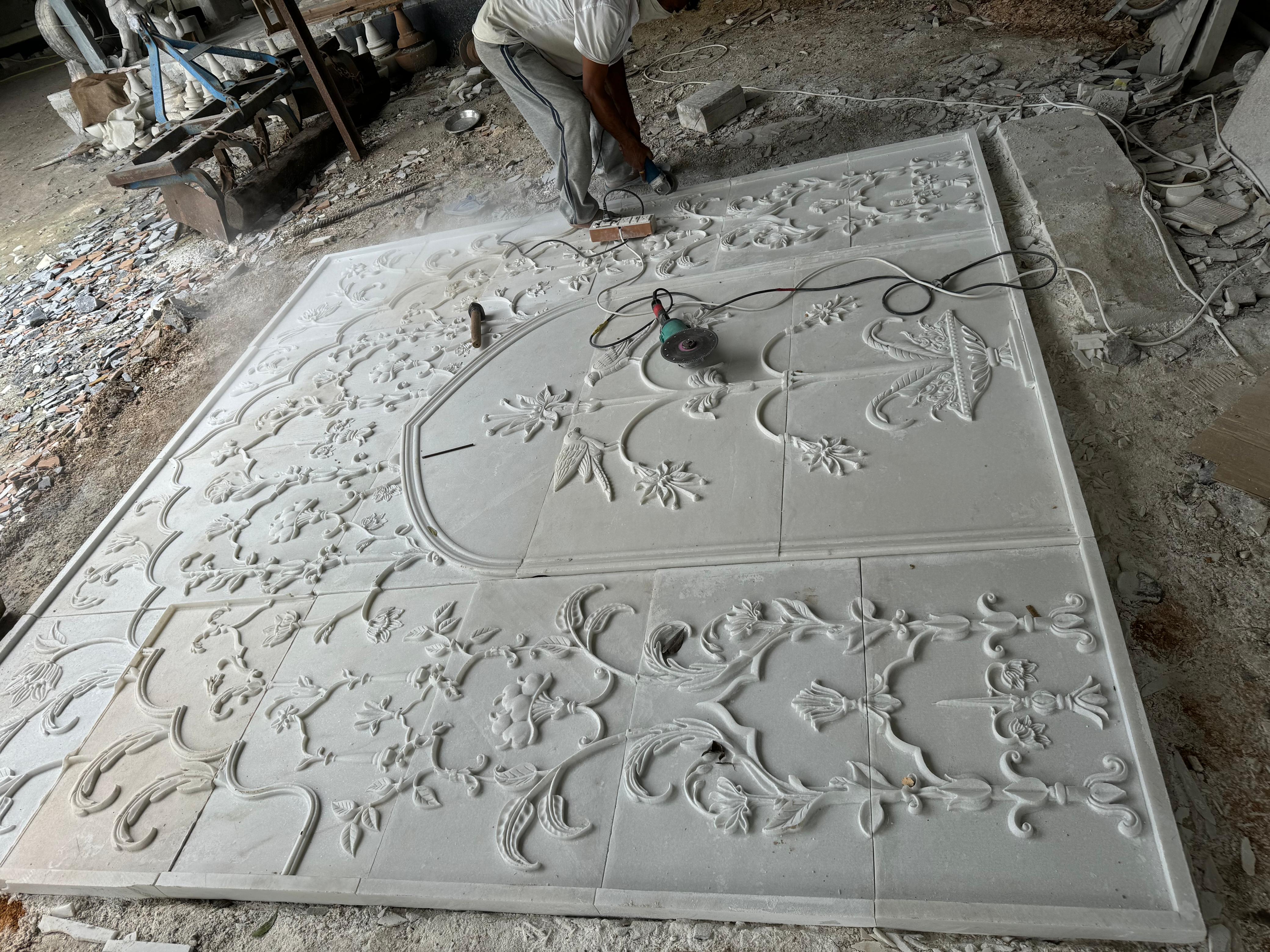 CNC-carved floral stone wall panel being finished by hand