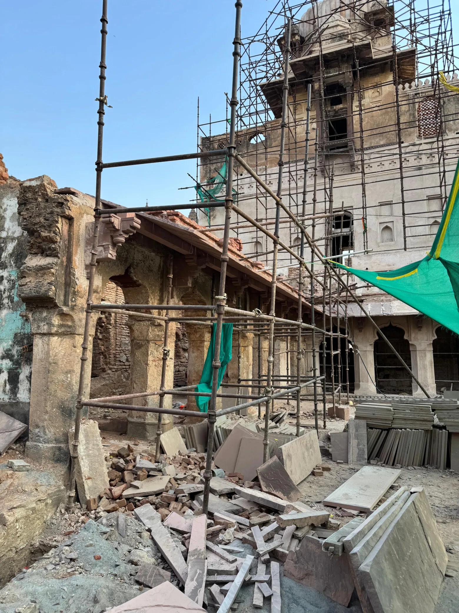 Replacement stone pieces stacked beside a damaged heritage arcade for reconstruction