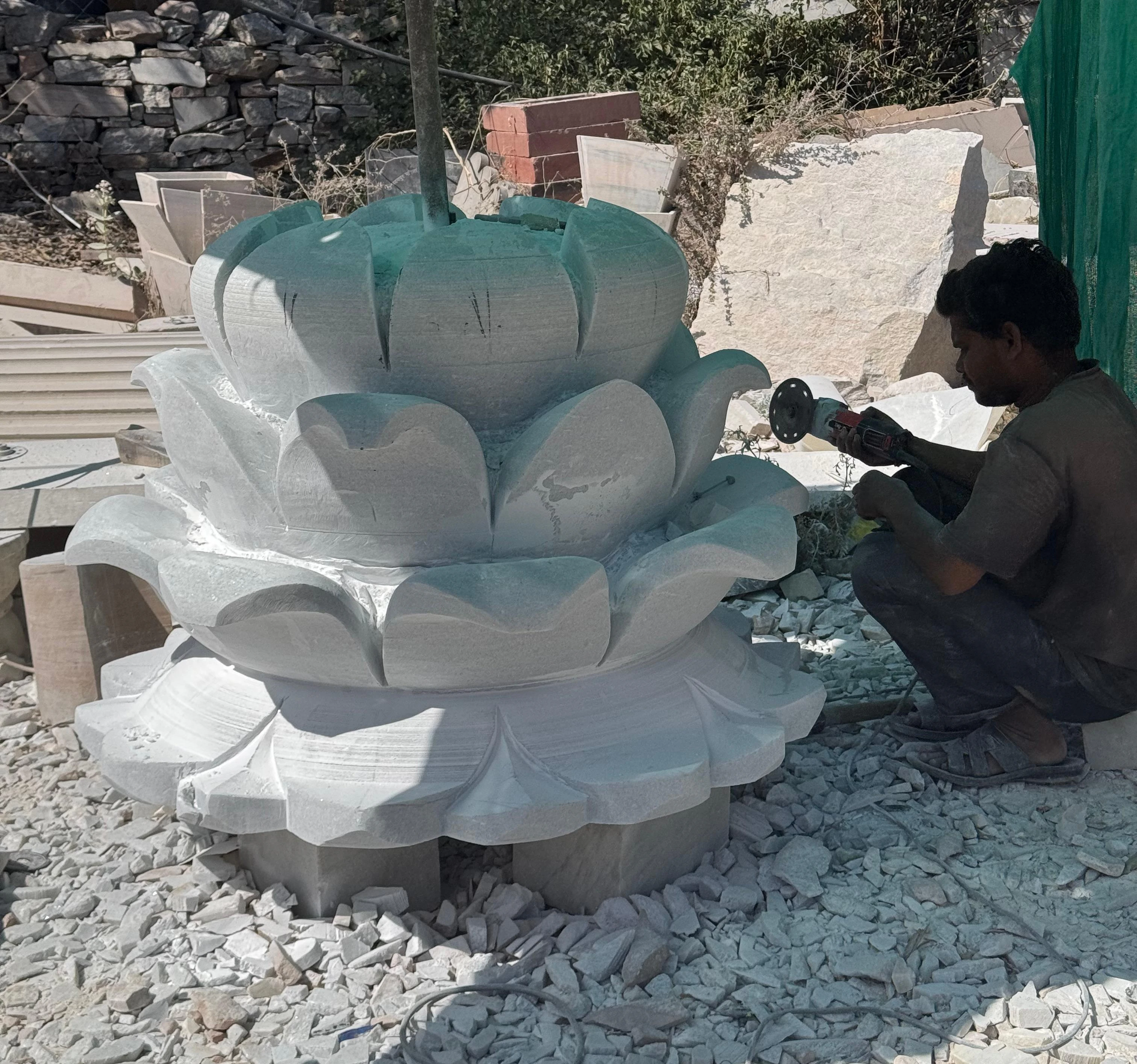 Craftsman finishing a large white marble lotus carving for export